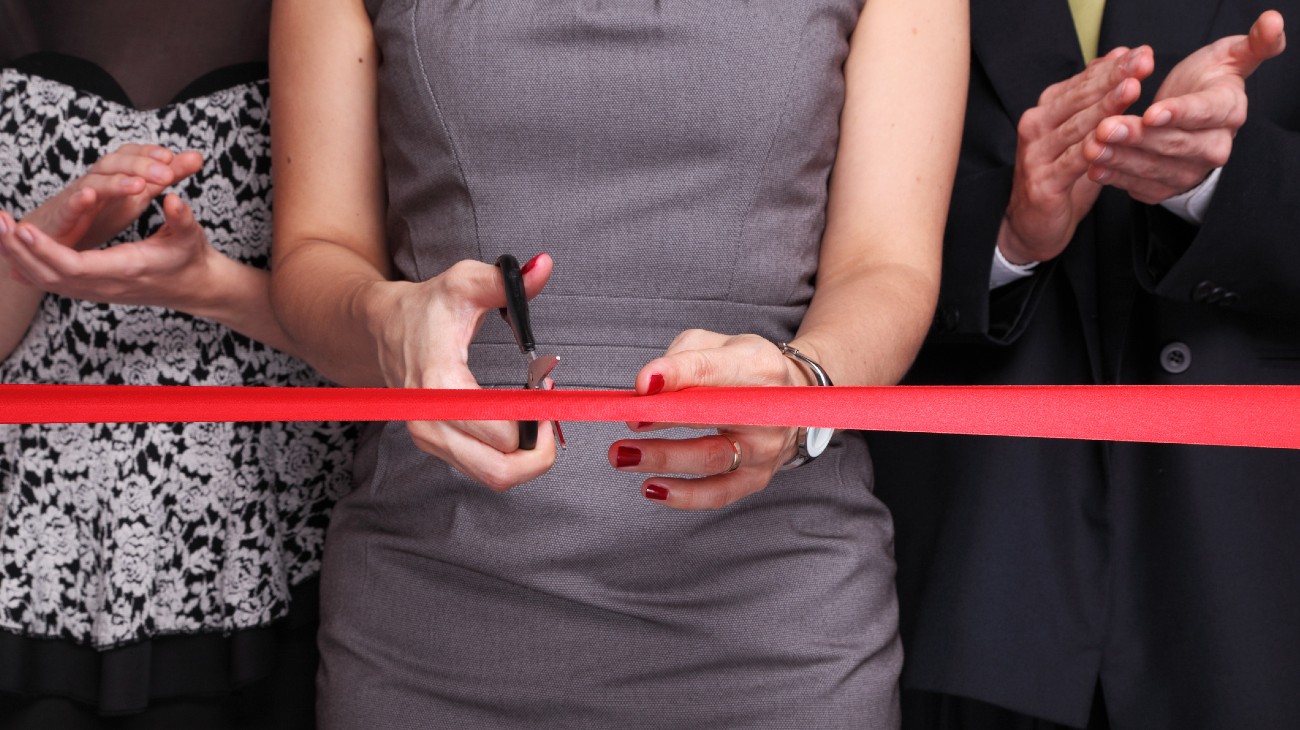 Business woman cutting tape at grand opening. What is an LLC?